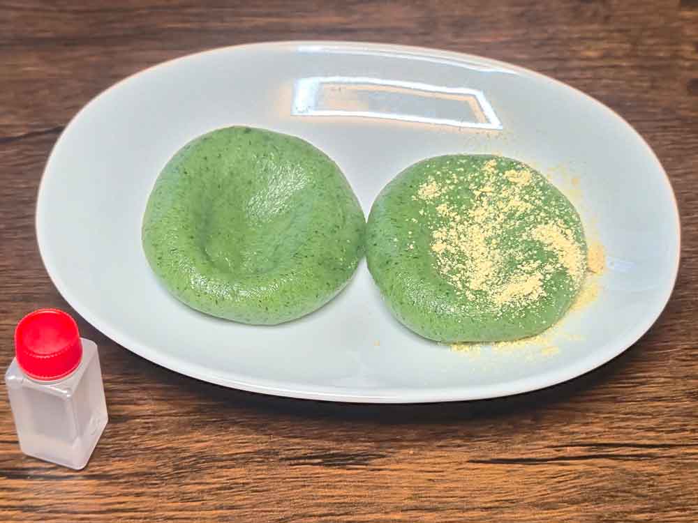 志満ん草餅の草餅（あんなし）。よもぎ色の草餅に、白蜜ときな粉を添えた提供例