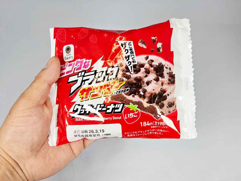 手に持ったピンクなブラックサンダードーナツのパッケージでサイズ感がわかる写真。