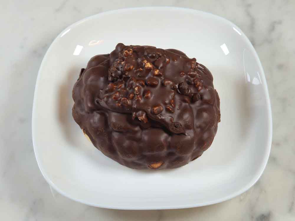 チョココーティングが全面にかかったメロンパンで、表面にゴツゴツしたチョコとビスケットの食感が見てわかる仕上がり。