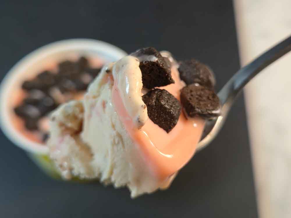 スプーンですくったストロベリーアイスとココアクッキー